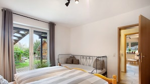 Un dormitori amb un llit, cortines i vista a l'exterior.