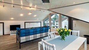 A modern interior with a sofa, dining table, and large windows. - Holiday Apartment "Andrea" with A/C & Wi-Fi (Bühl)