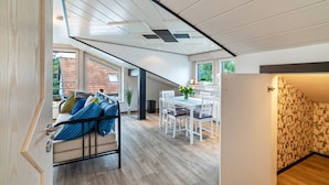 A modern interior with a dining area, a sofa with patterned cushions, and a view through a window. - Holiday Apartment "Andrea" with A/C & Wi-Fi (Bühl)
