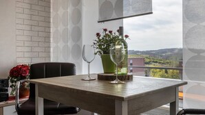 A balcony with a table, two wine glasses, a bottle, and a vase with red roses. - Holiday Apartment "Harzblick" with Mountain View, Balcony & Wi-Fi (Altenau)