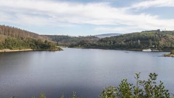A calm lake surrounded by hills and trees.