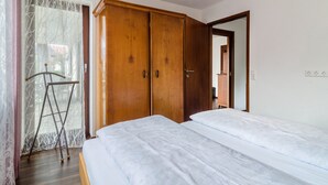 Une chambre à coucher avec une armoire en bois, un lit et une fenêtre avec un rideau.