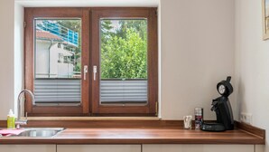 Une cuisine équipée d’un évier à deux bacs, d’un plan de travail en bois et d’une machine à café.
