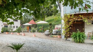 A courtyard with potted plants, a small building with a red roof, and a wooden door. - Holiday Home with Balcony, Terrace, Private Patio, Shared Garden and Wi-Fi (Salem)
