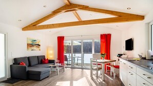 A modern living room with a sofa, dining table, and kitchen area. - Holiday Home with Balcony, Terrace, Private Patio, Shared Garden and Wi-Fi (Salem)