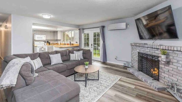 Ein modernes Wohnzimmer mit einem grauen Modulsystem, einem runden Couchtisch und einem Kamin.