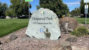 Ein großer Felsen mit der Inschrift 'Chaparral Park' und '130 Timmerman Dr.', umgeben von Kies und Steinen.