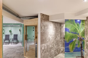Ein modernes Interieur mit einer Sitzecke, einer Wand mit Palmenmotiv und einer Treppe.