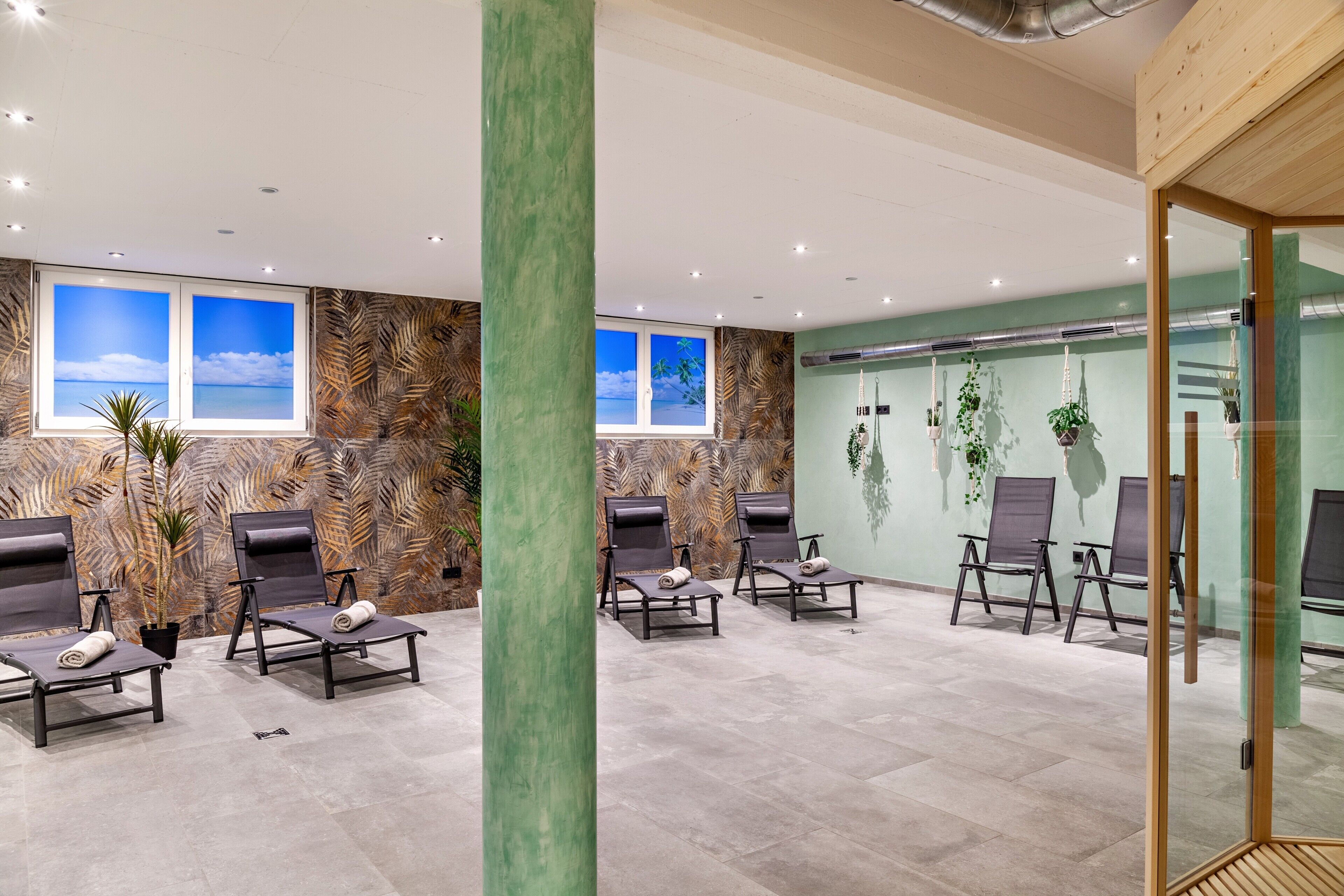 Ein moderner Wartebereich mit Lounge-Möbeln, einer großen Säule und Blick zum Himmel durch Fenster.