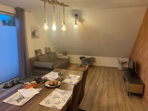 Una sala de estar acogedora con sofá, mesa de comedor y mueble para televisión.