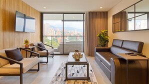A modern living room with a sofa, armchairs, a coffee table, and a TV mounted on the wall.