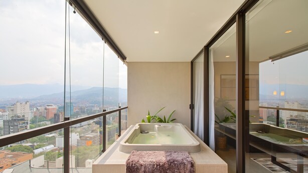 A balcony with a hot tub, a towel, and a view of the city.