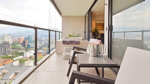 A balcony with a table, chairs, a small sofa, and a plant.