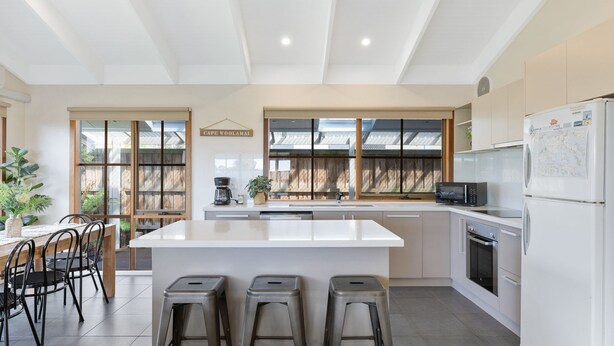 A modern kitchen with a central island, bar stools, a coffee machine, and a refrigerator. - Key Lime Retreat in Cape Woolamai (Cape Woolamai)