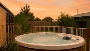 A hot tub in a backyard with a wooden fence and a building in the background. - Key Lime Retreat in Cape Woolamai (Cape Woolamai)