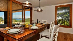 A dining area with a wooden table set for four, a view of the outdoors, and a large window. - Villa Vela Baraka with private Pool, Dragove, Croatia (Dragove)
