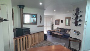 A living room with a wooden dining table, a sofa, a TV, and a fireplace. - Dunsborough Family Fun House! Walking distance to beach and town. (Dunsborough)