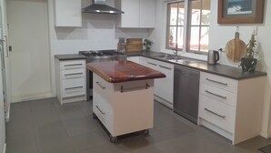 A modern kitchen with white cabinets, a stainless steel stove, and a wooden countertop. - Dunsborough Family Fun House! Walking distance to beach and town. (Dunsborough)