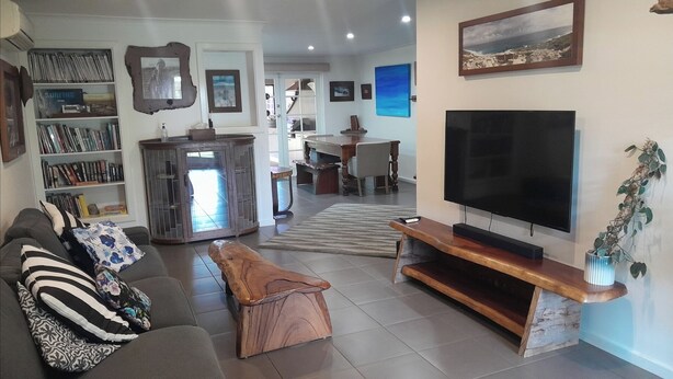 A living room with a sofa, coffee table, TV, and bookshelves. - Dunsborough Family Fun House! Walking distance to beach and town. (Dunsborough)