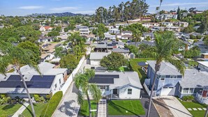 A residential area with houses, palm trees, and solar panels.