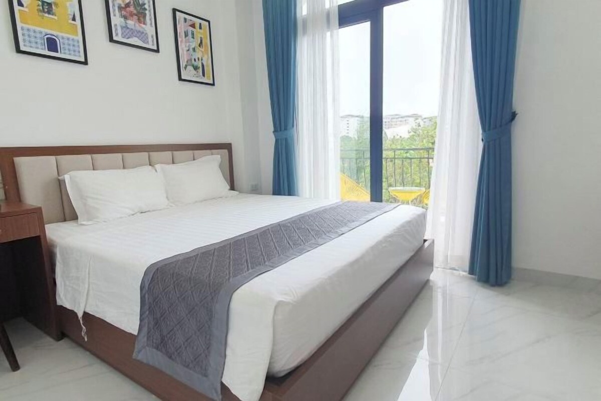 A bedroom with a bed, a nightstand, and a window with curtains.
