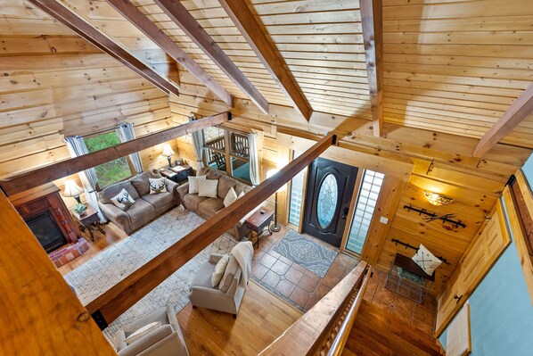 A wooden interior with a living area featuring a sofa, a fireplace, and a staircase leading to an upper level.