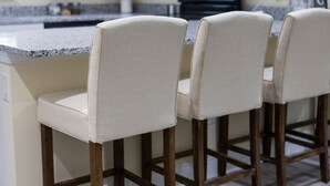 Une cuisine dotée d’un plan de travail en granit et de trois tabourets de bar avec des assises rembourrées.