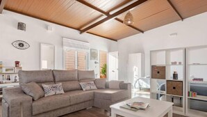 A spacious living area with a large sectional sofa, a white coffee table, and built-in shelving with storage boxes. - Rincón Andaluz, Huerta Alegría (Casariche)