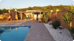 A swimming pool with a concrete pathway leading to a building with a flat roof. - Rincón Andaluz, Huerta Alegría (Casariche)