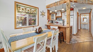 Una cocina con isla de madera, armarios blancos e iluminación colgante.