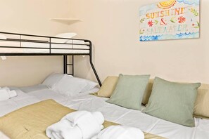 Un lit superposé avec une literie blanche et un seul oreiller vert.
