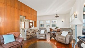 Un amplio salón con chimenea, sofás de cuero, una mesa de comedor y una cocina al fondo.