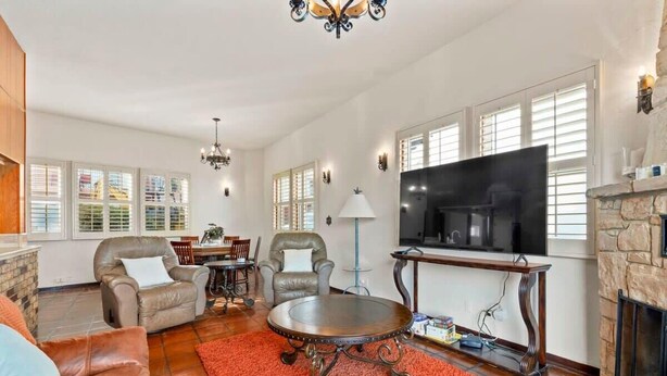 A spacious living room with a fireplace, a large flat-screen TV, leather armchairs, and a round coffee table.