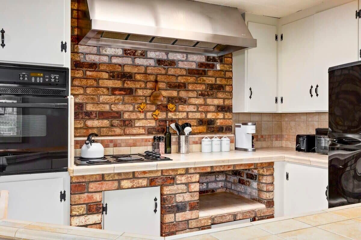 Eine Küche mit Backsteinrückwand, weißen Schränken und einem eingebauten Backofen.