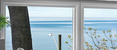 Una habitación con un ventanal grande que da a un cuerpo de agua, un poste de madera y una lámpara.