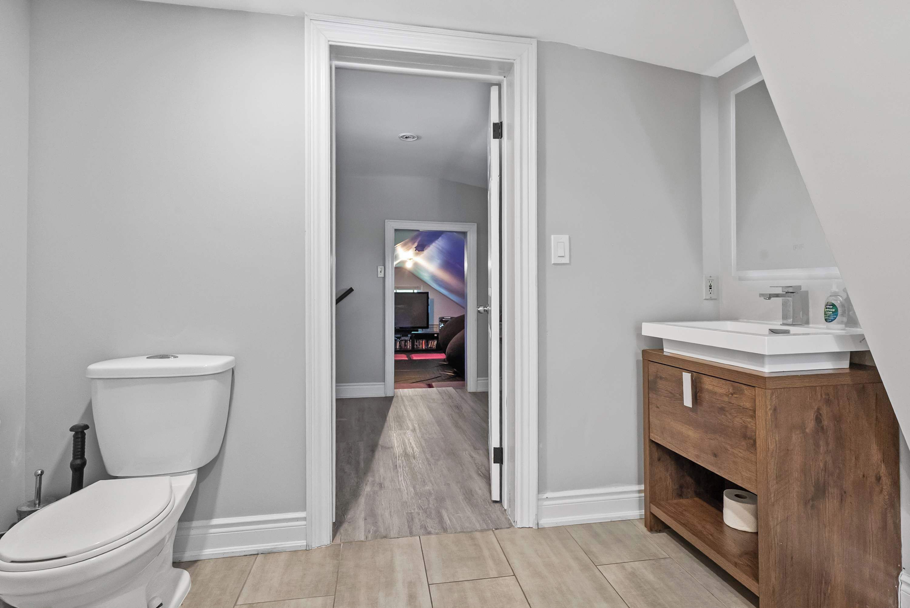 A bathroom with a toilet, a wooden vanity, and a shower area.