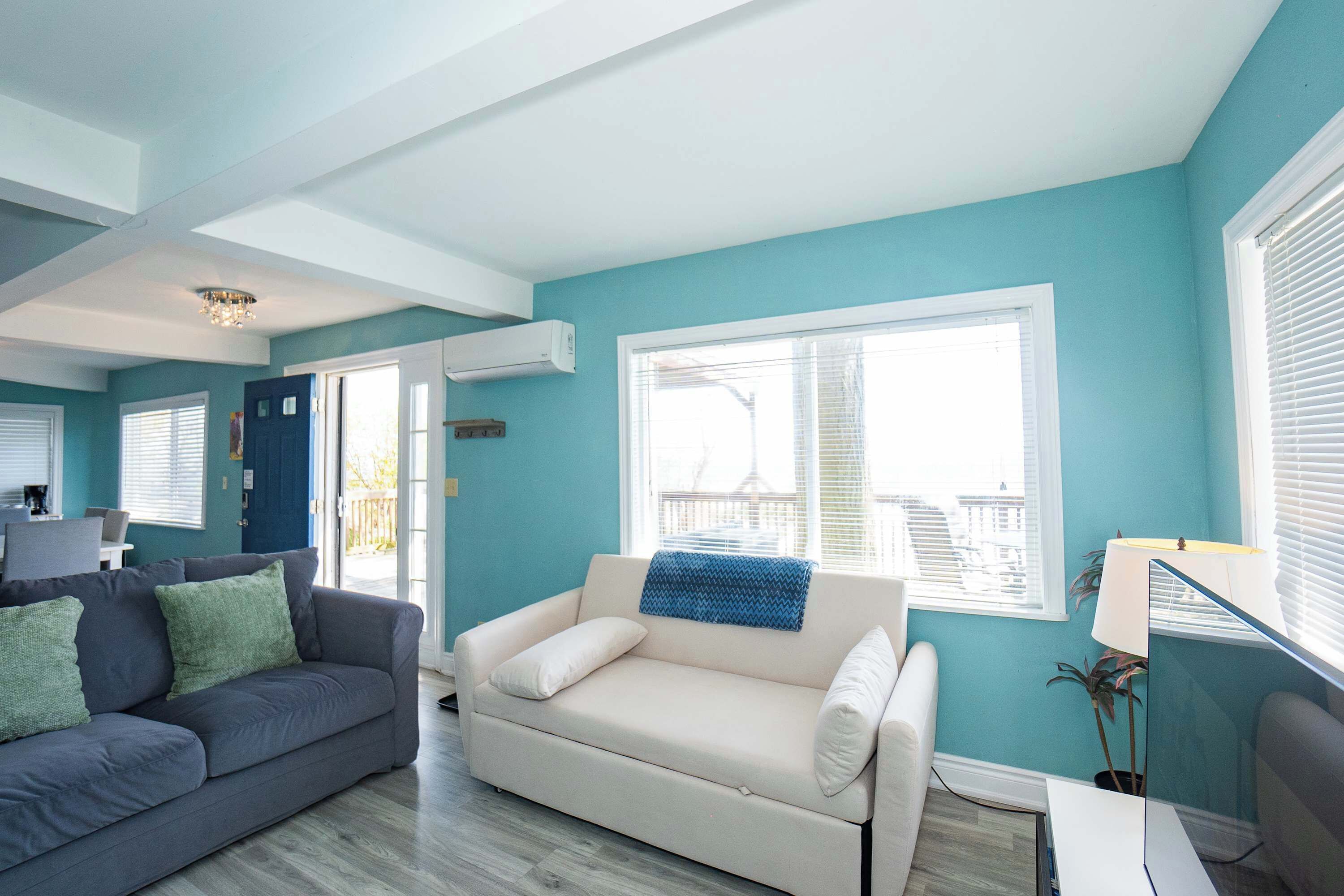 A living room with a grey couch, a white sofa, and a blue accent wall.