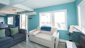 Een woonkamer met een grijze bank, een witte divan en een blauwe accentmuur.