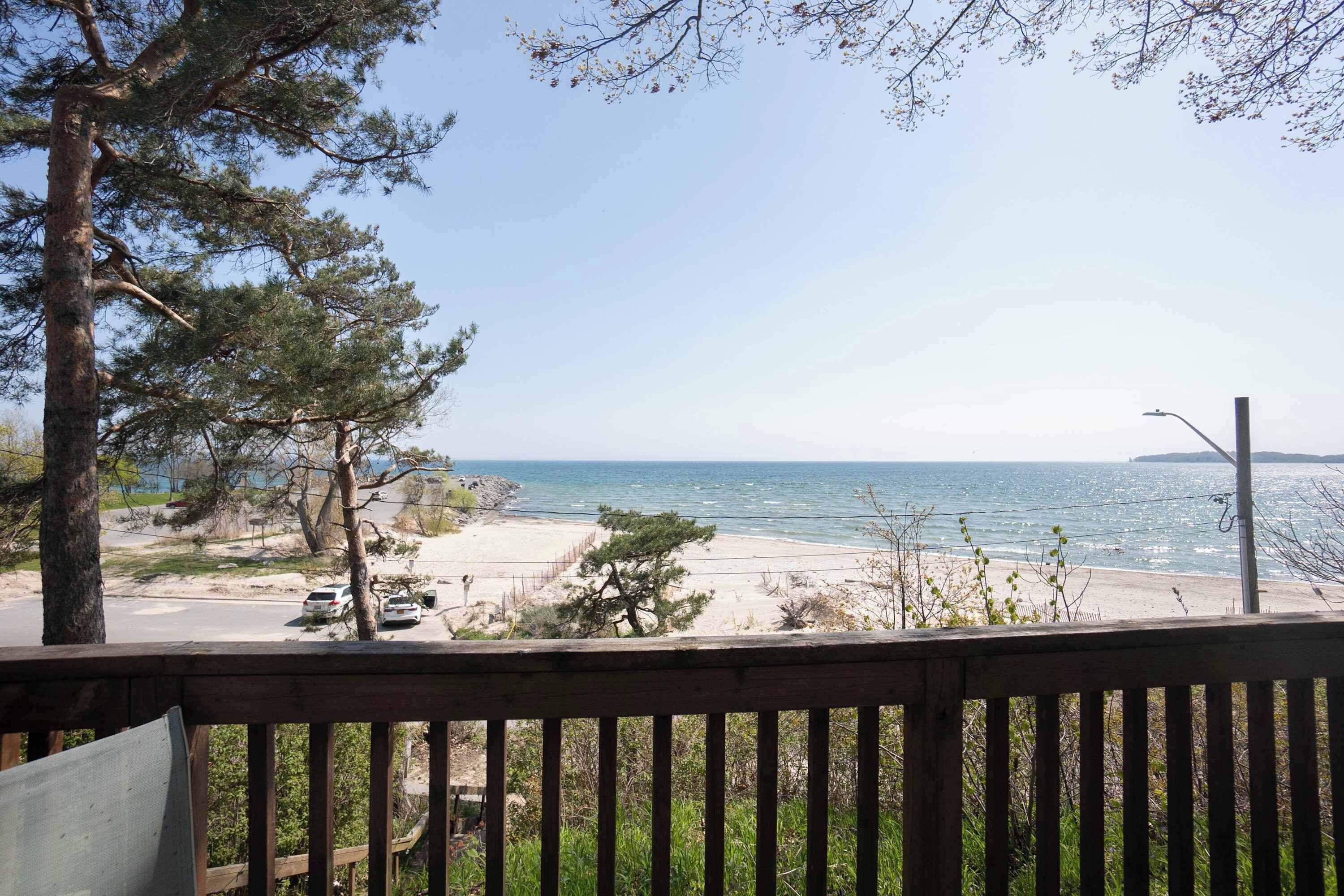 En vy över stranden från en träveranda, med en klar himmel, en sandstrand och några bilar parkerade längs vägkanten.