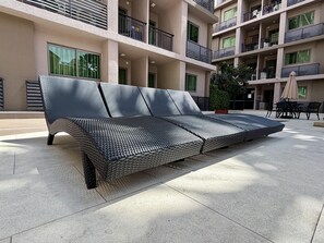 A modern outdoor seating area with a metal-framed sofa and a dining table with chairs. - Arcadia Beach Continental (Pattaya)
