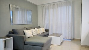 Una sala moderna con un sofá seccional gris, una mesa de centro blanca y una mesita auxiliar blanca.