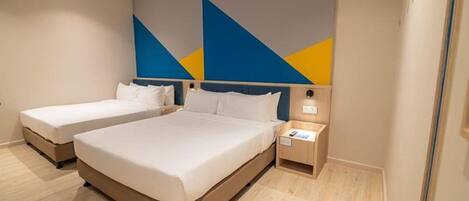 A hotel room with two beds, a bedside table with a lamp, and a wall with geometric patterns.