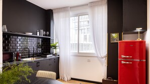 A modern kitchen with black and white tiles, a red refrigerator, and a dining area with a table and chairs. - Artistic Vibes Haifa Hub by Sea N' Rent (Haifa)