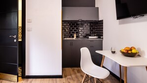 A compact kitchen with a black backsplash, a white dining table, and a TV mounted on the wall. - Artistic Vibes Haifa Hub by Sea N' Rent (Haifa)