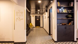 A hallway with a patterned floor, a bookshelf with books and decorative items, and a door at the end. - Artistic Vibes Haifa Hub by Sea N' Rent (Haifa)
