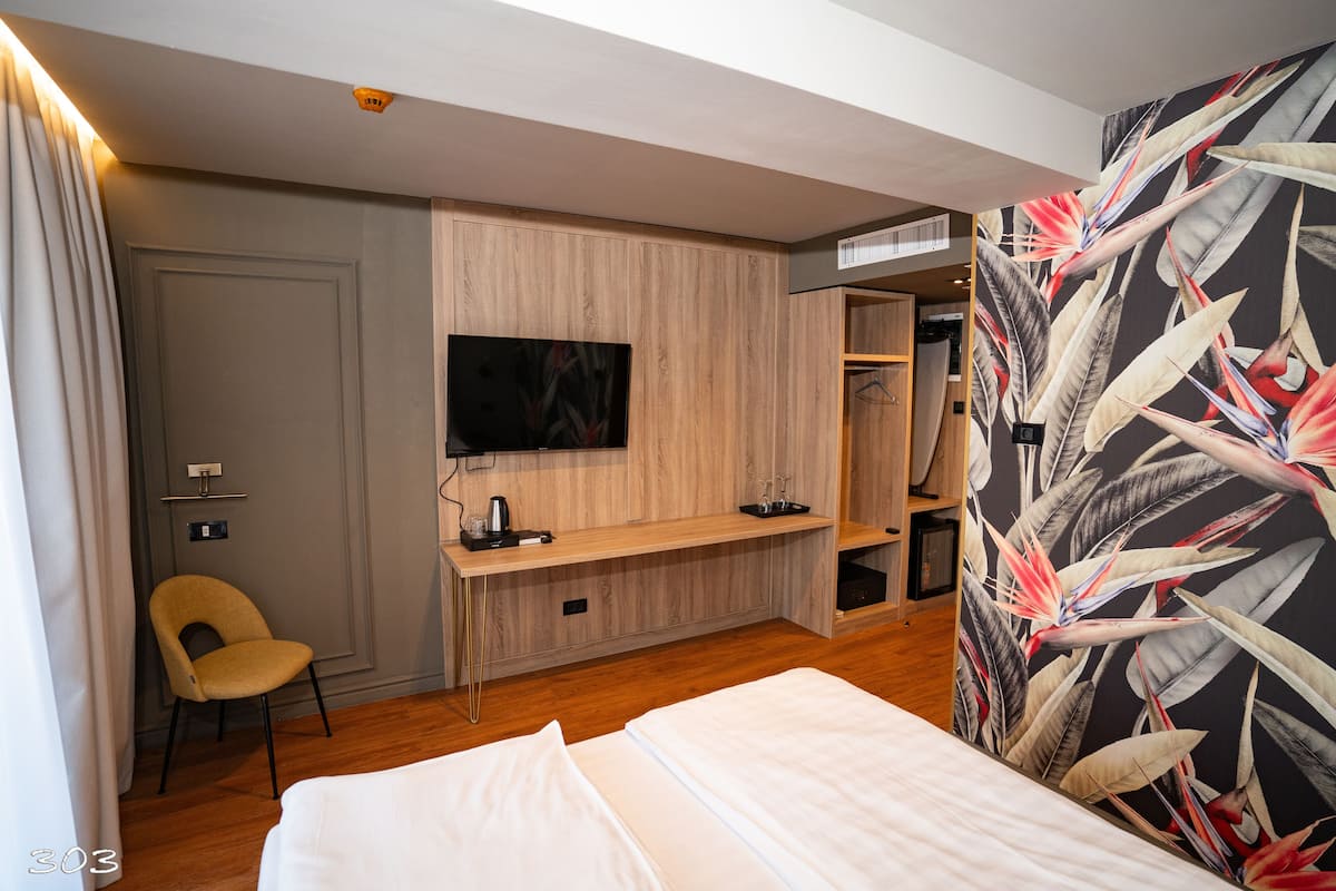 Ein Hotelzimmer mit Bett, Schreibtisch, Flachbildfernseher, Stuhl und Kleiderschrank.