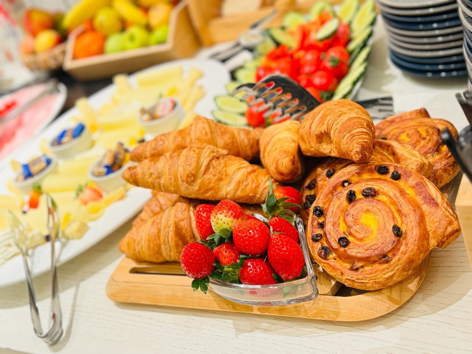A buffet table with various food items including croissants, strawberries, and other pastries.