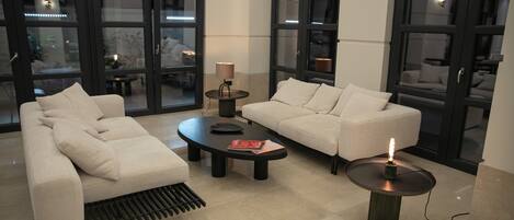 Una sala de estar moderna con un sofá beige, una mesa de centro y una mesita de noche con una lámpara.