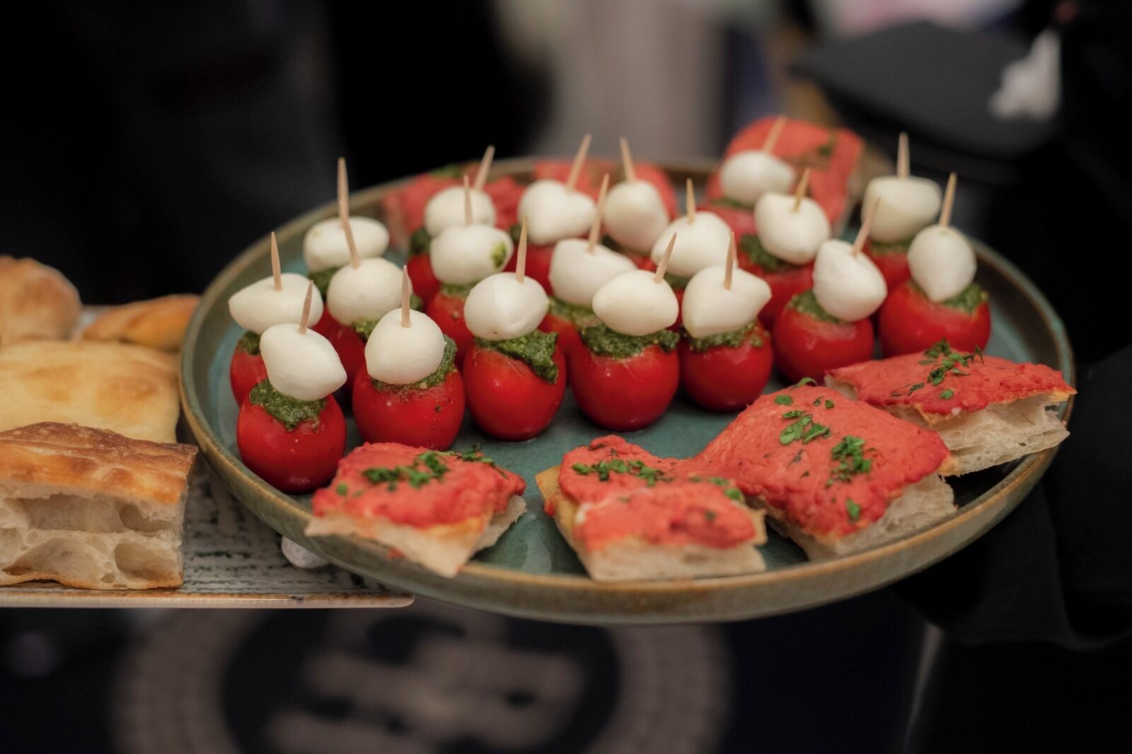 Une assiette de nourriture comprenant des tomates cerises farcies au fromage et une tranche de pain tartinée de purée de tomates.