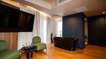 Una sala de estar moderna con un sillón verde, una bañera negra y un televisor de pantalla plana.